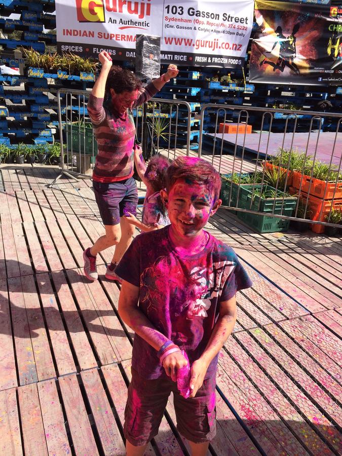 Boy throwing pink Holi powder into the air on the deck