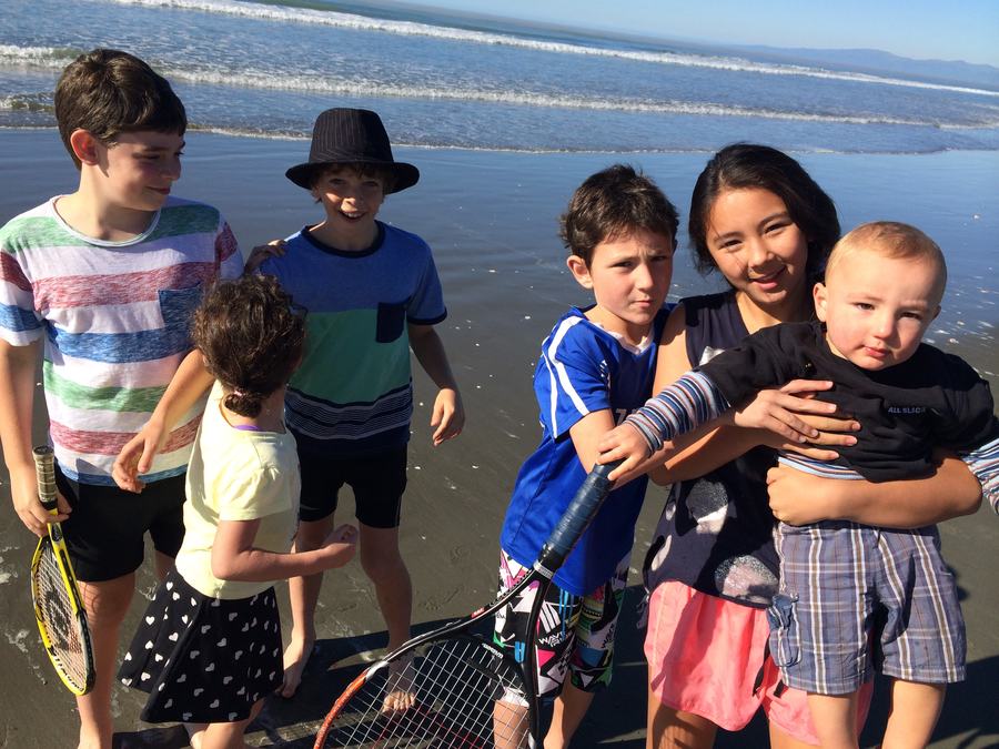 Children with tennis rackets on the beach