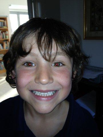 Close-up of a smiling boy with dark curly hair indoors