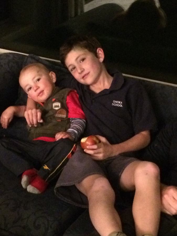 Two brothers on the sofa, the younger holding an apple