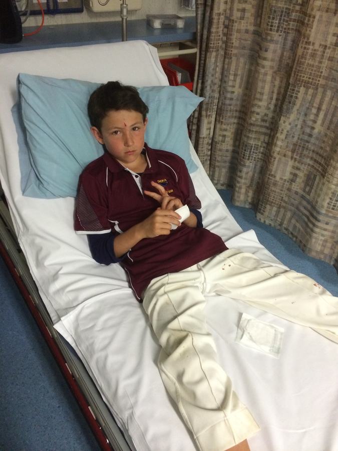 Boy in a maroon sports top lying in a hospital bed