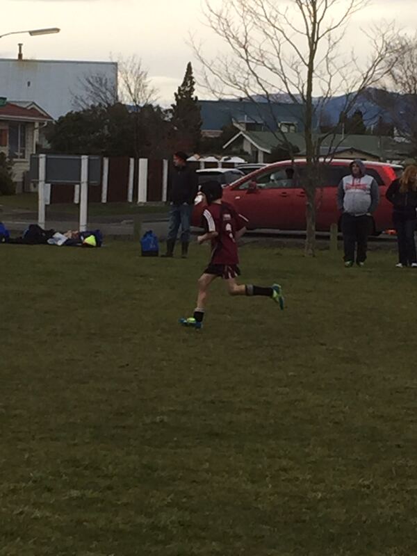 Boy running with the ball during a football game on a neighbourhood field