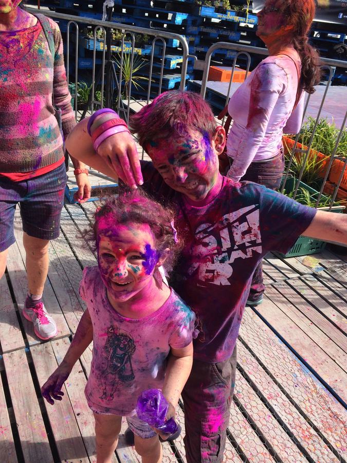 Two children covered in bright Holi colour on the deck