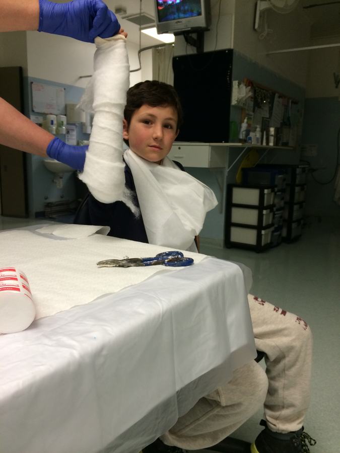 Boy holding up his newly plastered arm at the clinic