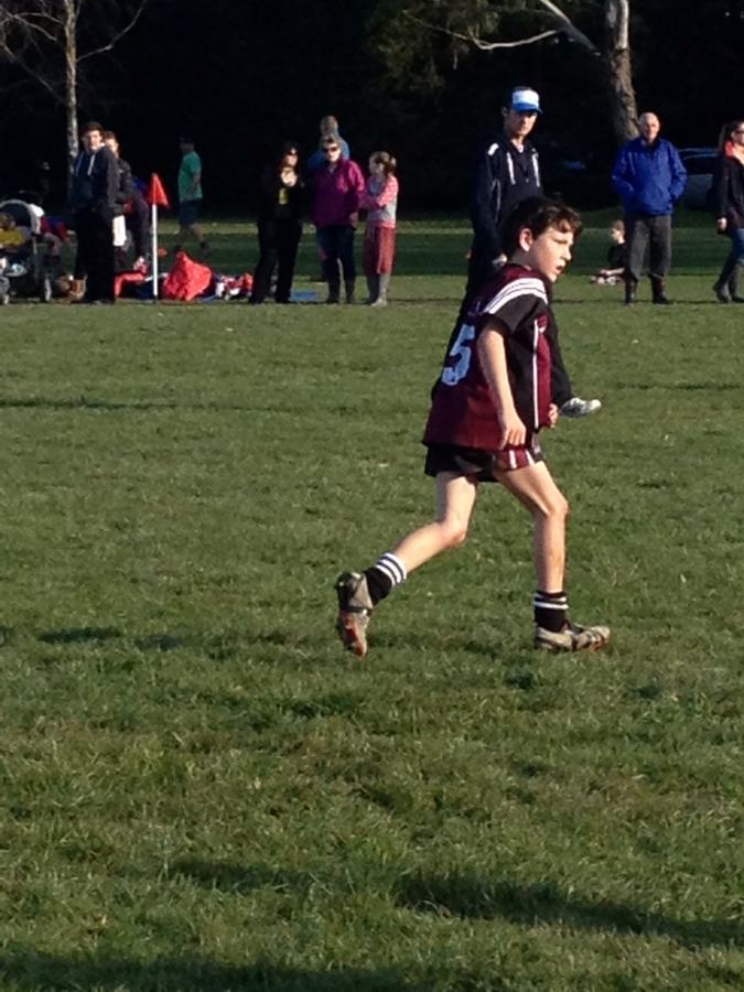Boy running with a ball on the field at dusk