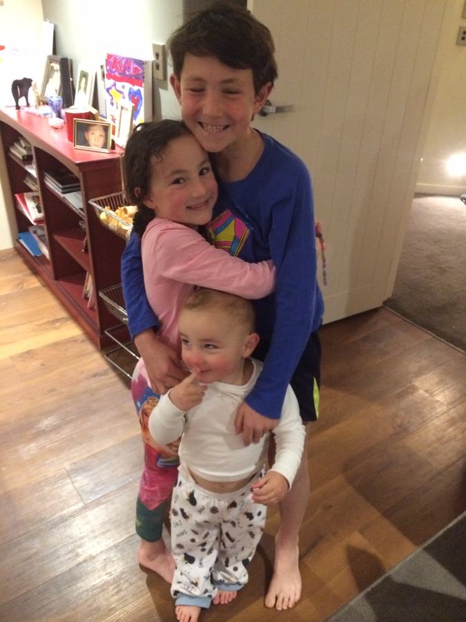 Three siblings hugging in the hallway