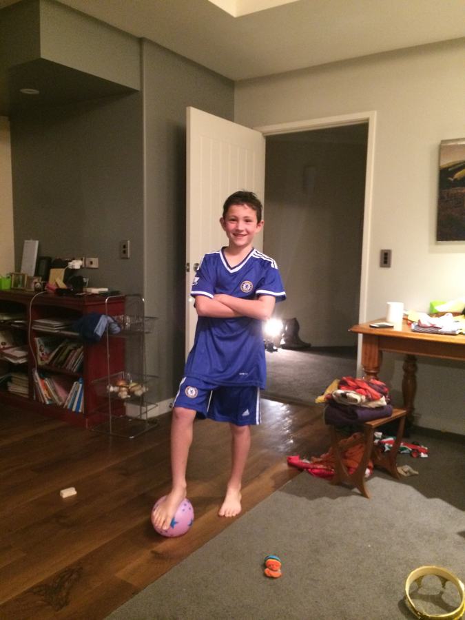Boy in a blue football kit playing indoors