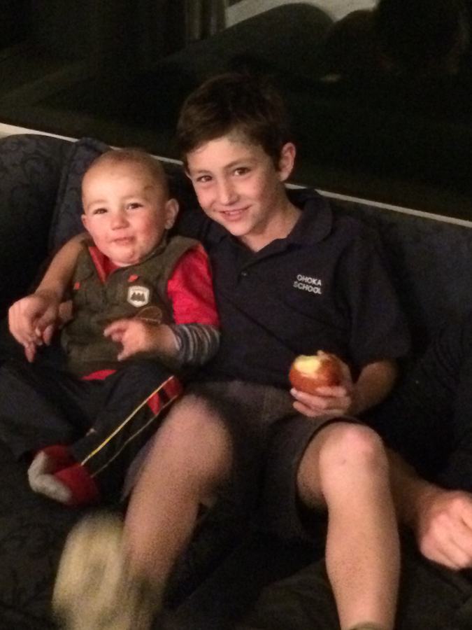 Two boys sharing the sofa in the evening