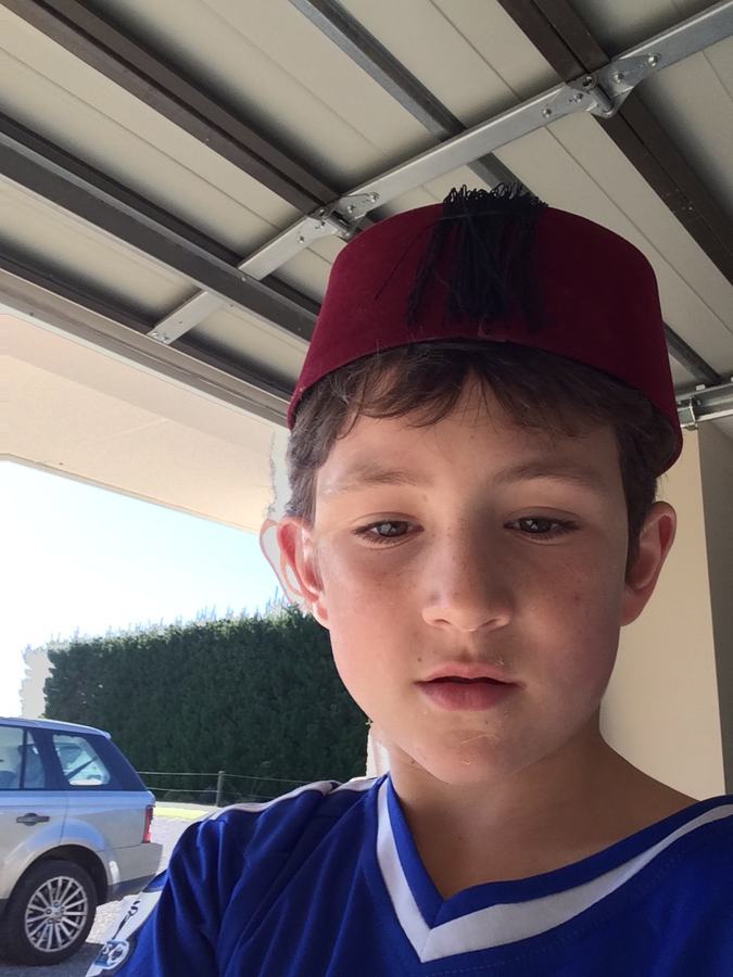 Boy in a maroon cap outside beside the car