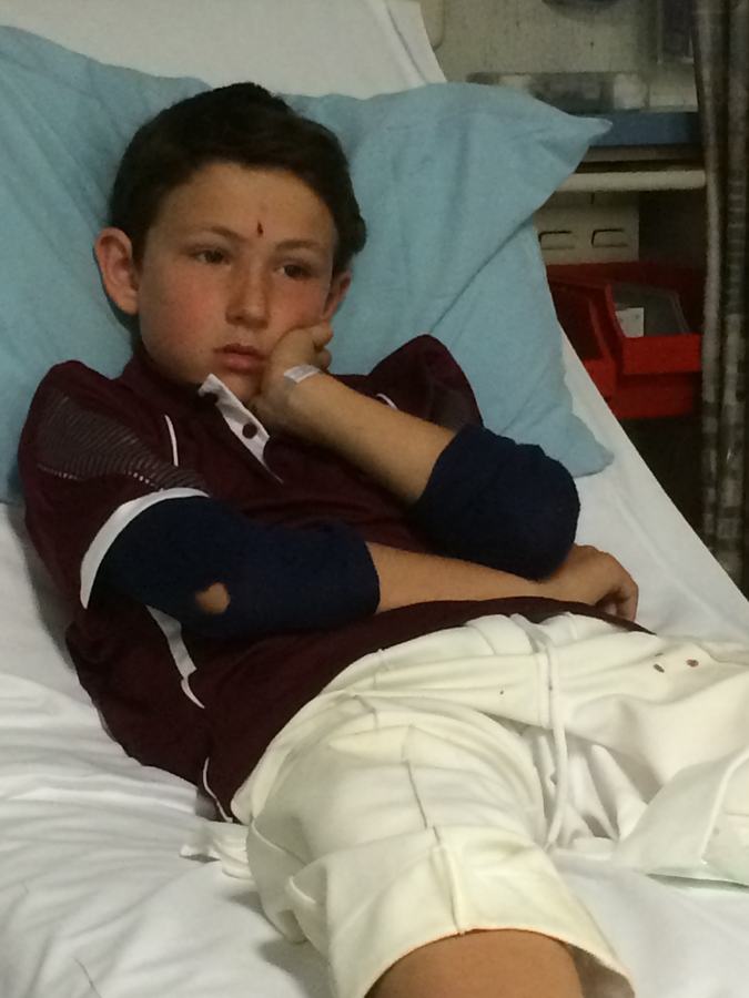 Boy in rugby kit resting in a hospital bed