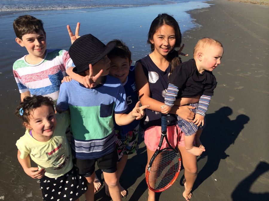 Group of children on the beach making peace signs
