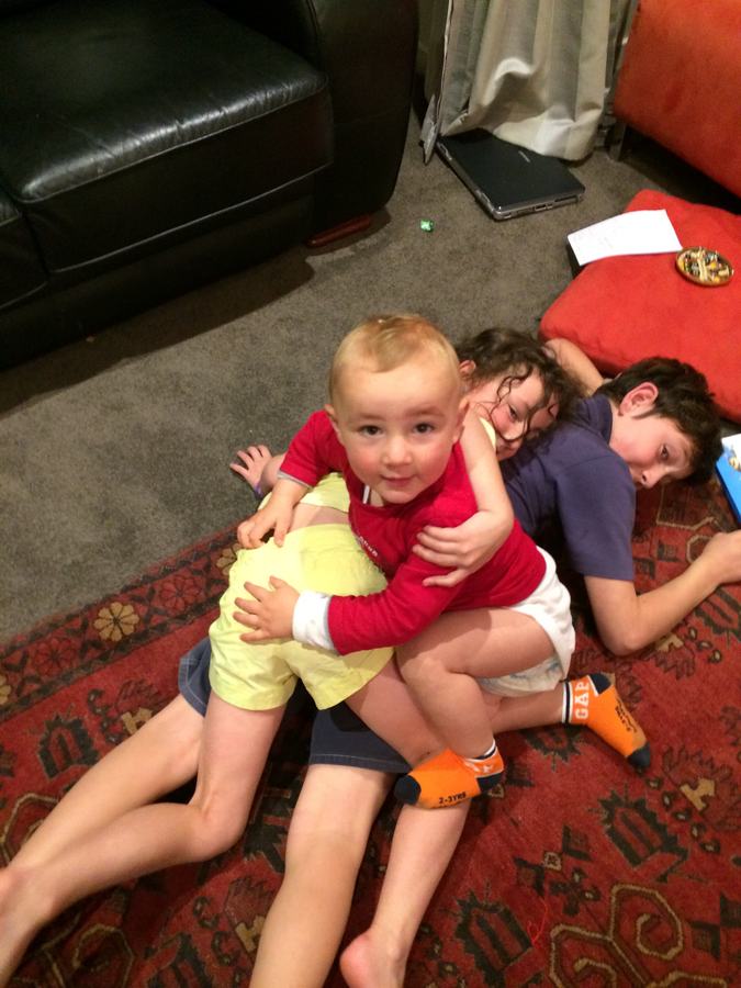 Toddler and older children hugging on the rug